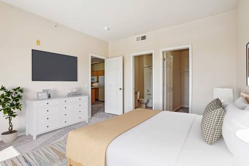 A bedroom with a large bed, a TV, and a cabinet.