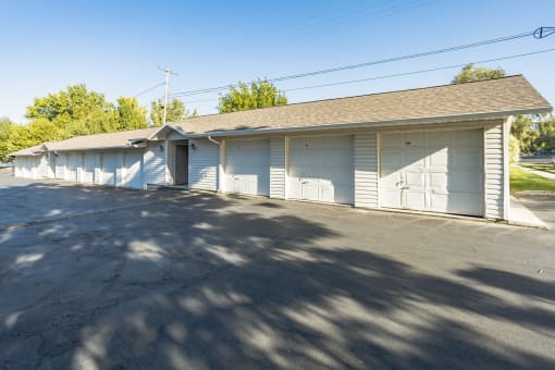 a white garage with white doors and a street in front of it