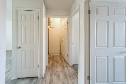 an empty hallway with white doors and a closet