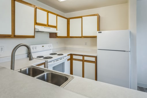 an empty kitchen with white appliances and white cabinets