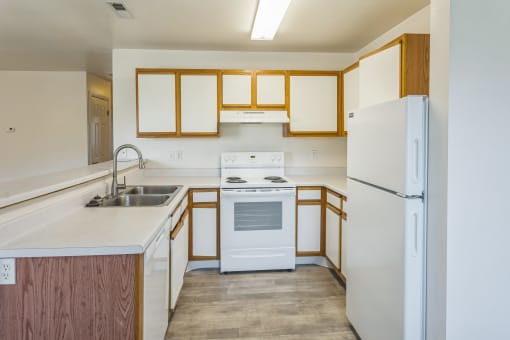 an empty kitchen with white appliances and wooden cabinets