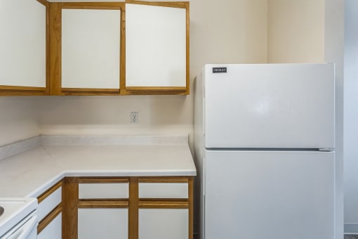 an empty kitchen with a refrigerator and cabinets