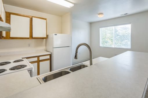 an empty kitchen with white appliances and a sink