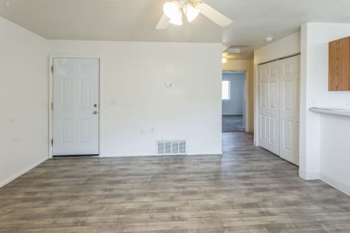 an empty living room and kitchen with white walls and wood flooring