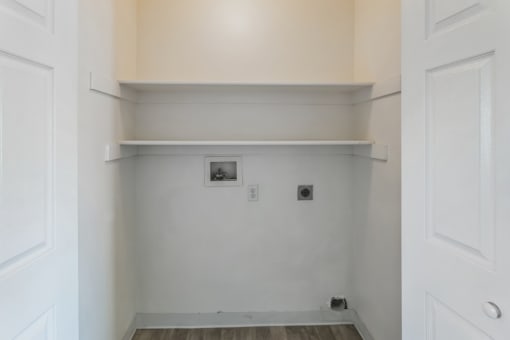 a room with white walls and a white shelf and a door