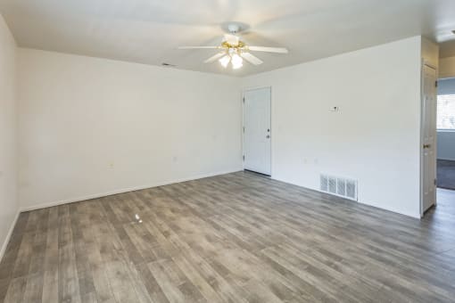 an empty living room with white walls and a ceiling fan