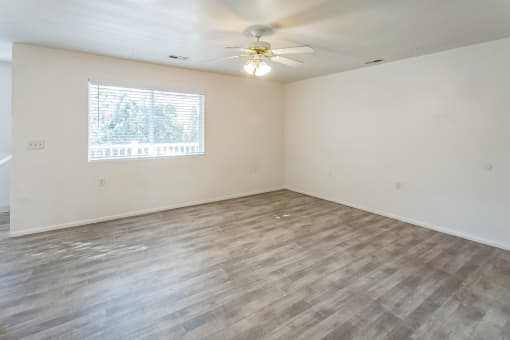 an empty living room with a window and a ceiling fan