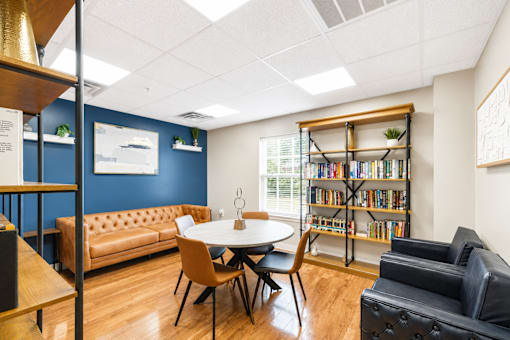 A room with a round table and chairs, a bookshelf, and a couch.