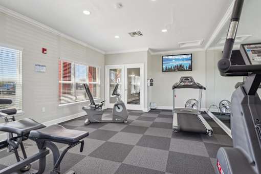 A gym with a variety of equipment including treadmills, stationary bikes, and weight machines.