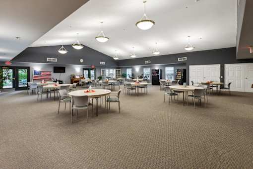 A large room with tables and chairs and a carpeted floor.