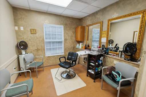 A room with a chair, mirror, and fan.