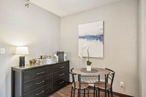 A dining table with chairs and a cabinet with drawers is in a room.