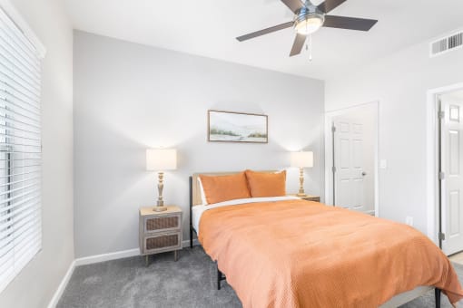 a bedroom with an orange bed and a ceiling fan