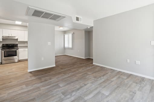 the living room and kitchen of an apartment with white walls and wood flooring at Vista Linda, Santa Fe, 87507