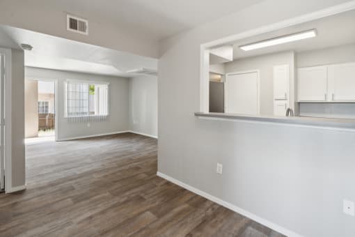 an empty living room and kitchen with white walls and wood flooring at Vista Linda, Santa Fe, 87507