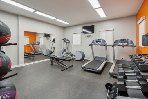 A gym with orange walls and a variety of equipment. at Vista Linda, Santa Fe, NM