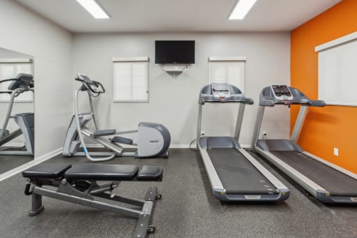 two treadmills and other exercise equipment in a gym with a tv at Vista Linda, Santa Fe, New Mexico