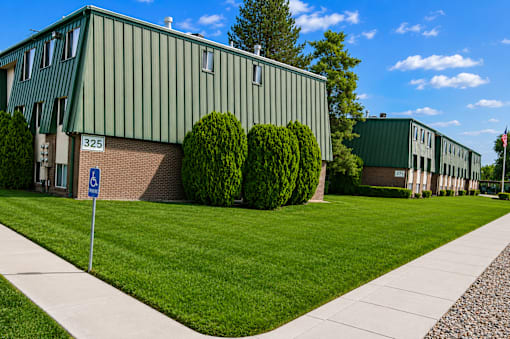 A green building with a blue sign in front of it at The Morgan Apartments, Apartments, Layton, UT
