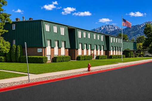 A green building with a flag on top and a red fire hydrant in front at The Morgan Apartments, Layton, 84041