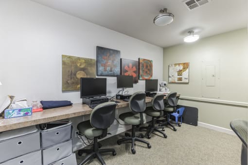 a room with a long desk with computers and chairs