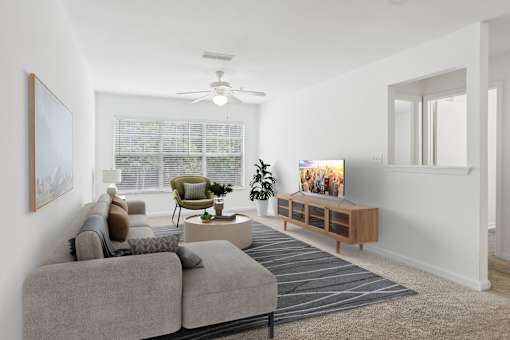 A living room with a grey sofa, a green armchair, a coffee table, and a television.