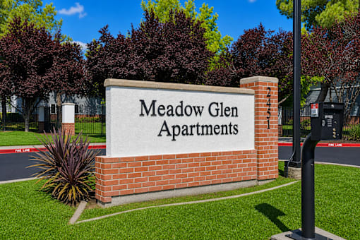 A sign that says Meadow Glen Apartments in front of a building.