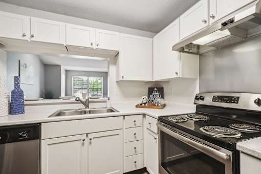 A modern kitchen with white cabinets and stainless steel appliances.