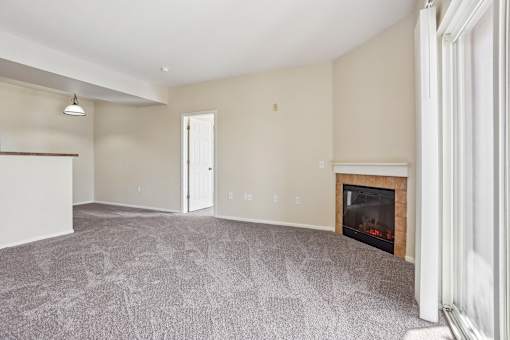 A living room with a fireplace and a grey carpet.