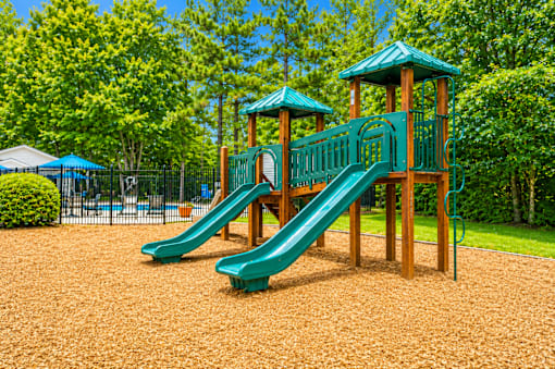 A playground with a green slide and wooden structure.