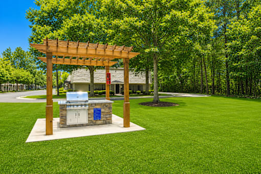 A wooden pergola with a grill on a patio.