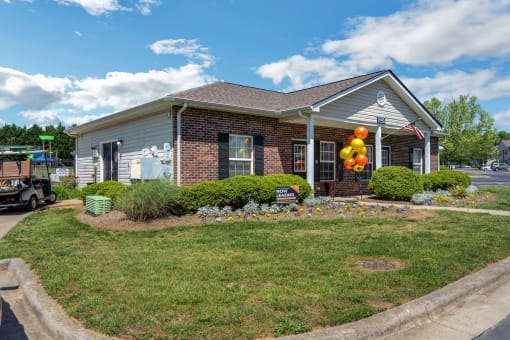 the front of a house with a yard and a balloon arrangement