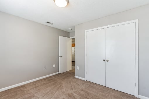 a bedroom with white closets and a door to a hallway