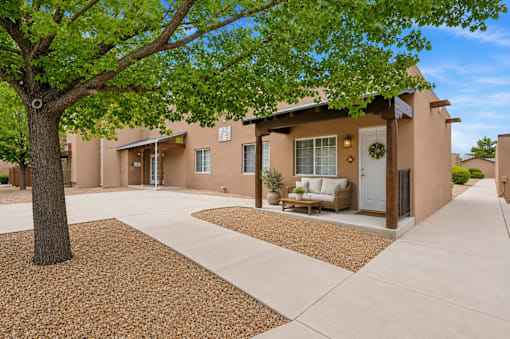 A tree is in front of a building with a white door and windows.