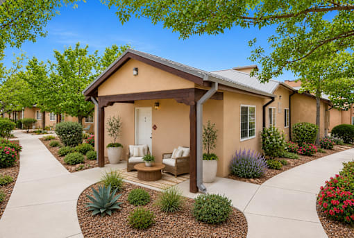 A small house with a porch surrounded by a garden.