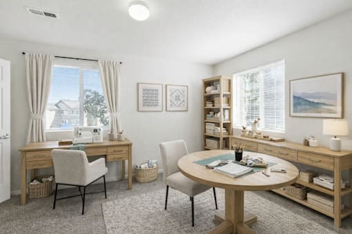 A well-lit room with a desk, chair, and a round table with a blue cushion. at Diamond Fork Apartments, Spanish Fork, UT, 84660