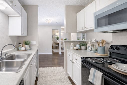 A kitchen with white cabinets and a black stove top. at Parkland at Orange Park Apartments , Orange Park
