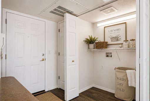 A laundry room with a sign on the wall and a basket of plants on the shelf.