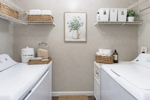 A laundry basket sits on top of a washing machine in a small laundry room. at Parkland at Orange Park Apartments , Florida