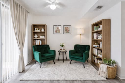 A living room with two green chairs and a white rug.