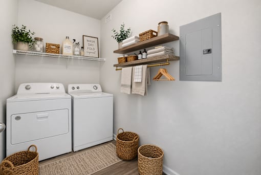 A laundry room with a washer and dryer and a basket on the floor.