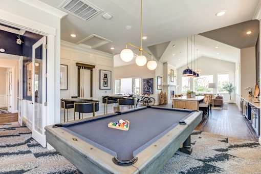 A pool table is in the middle of a room with a striped rug.