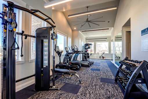 A gym with a variety of equipment including treadmills, stationary bikes, and weight machines.