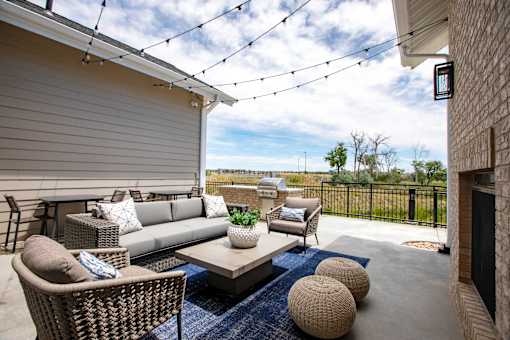 A patio with a sofa, chairs, and a table with a potted plant on it.
