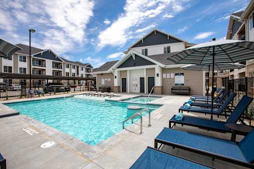 A swimming pool surrounded by lounge chairs and umbrellas.
