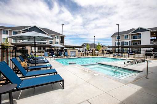 A pool area with sun loungers and a building in the background.