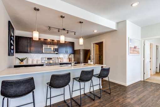 A kitchen with a bar area and three chairs.