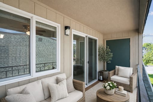 A balcony with a sofa, chairs, and a coffee table.