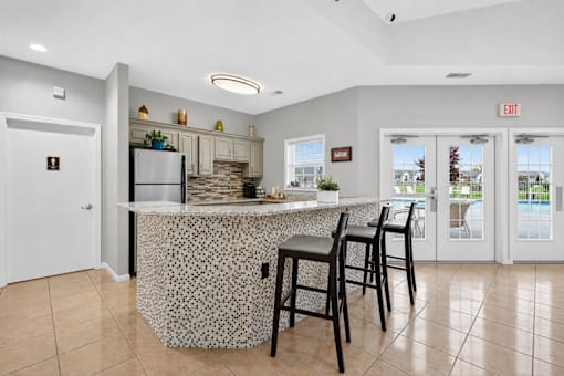 A kitchen with a bar and chairs.