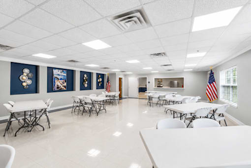 A room with tables and chairs and flags on the wall.
