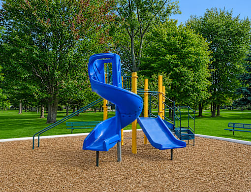 Playground with spiral slide and wood chips at Northview Park Apartments, Sterling Heights